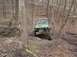 1992 Ford Bronco - A green off-road vehicle navigates a challenging, wooded terrain.