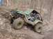 1992 Ford Bronco - A heavily modified off-road vehicle tackles a challenging muddy trail with a driver inside.