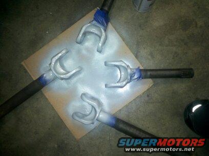 four driveshaft yokes being spray painted silver