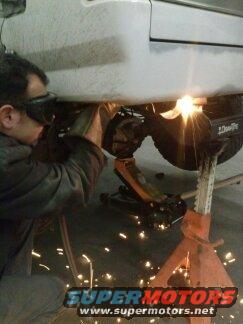 Welder working on vehicle undercarriage with sparks flying