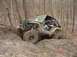 1992 Ford Bronco - An off-road vehicle navigates a challenging muddy terrain in a wooded area.