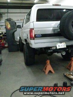White 1995 Ford Bronco in garage, rear view, on jack stands with spare tire mounted on back