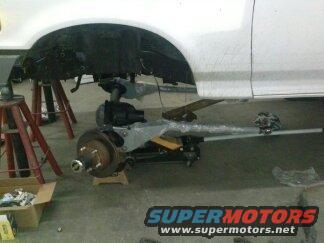 White vehicle's front end is jacked up, showing suspension and frame work. Supermotors.net logo visible