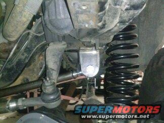 Close-up of suspension with coil spring and tie rod end. Supermotors logo visible