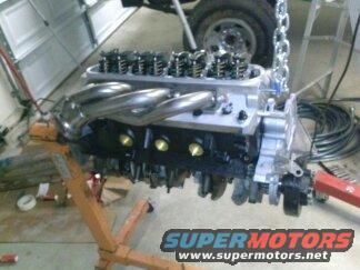 Engine on stand, chrome headers, SuperMotors logo visible