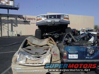 1995 Ford Bronco lifted high, crushing two wrecked cars