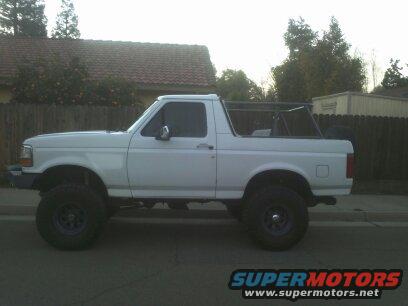 White 1995 Ford Bronco side view, lifted with roll cage