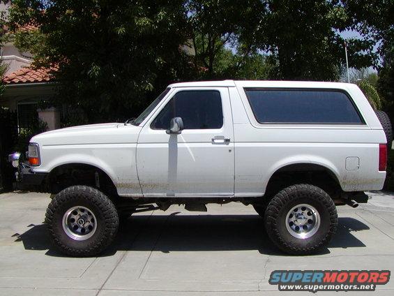 white 1995 Ford Bronco lifted with large tires, side view