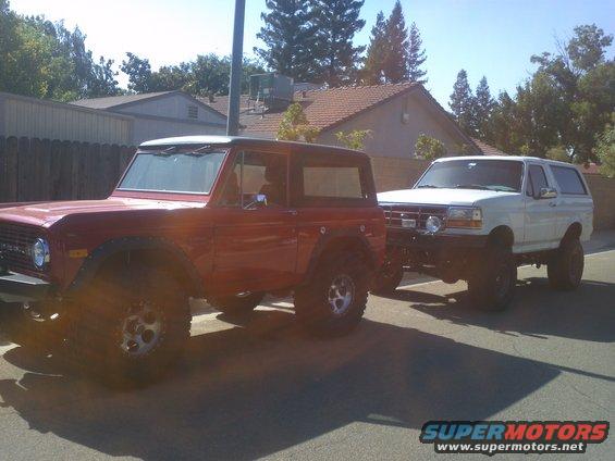 Red first-generation Ford Bronco next to a white fourth-generation Ford Bronco
