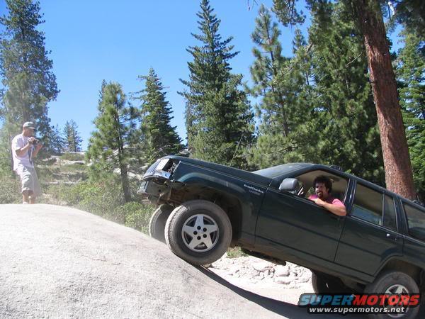 Dark green SUV climbing a rock face, driver visible