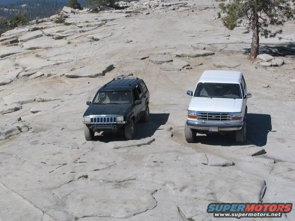 White Ford Bronco and green Jeep Grand Cherokee parked on a rocky slope
