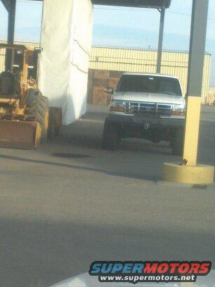 1995 Ford Bronco parked next to a yellow backhoe
