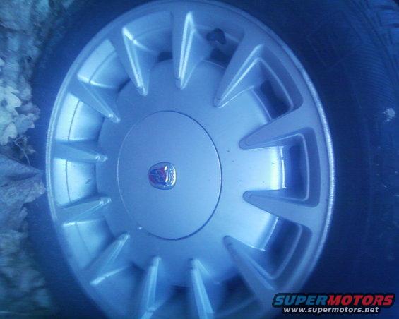 Close-up of a silver wheel cover with a red and blue emblem in the center