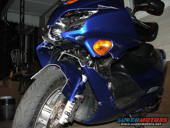Front view of a blue scooter with a cracked and damaged front fairing and turn signal