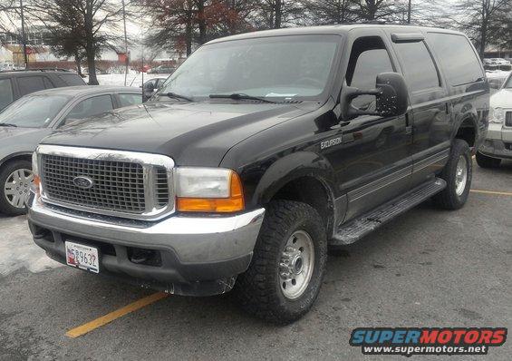 Black Ford Excursion SUV parked in a lot, front 3/4 view. Visible "EXCURSION" badge on fender