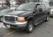 2001 Ford Excursion - A black Ford Excursion SUV is parked in a lot with other vehicles visible in the background.