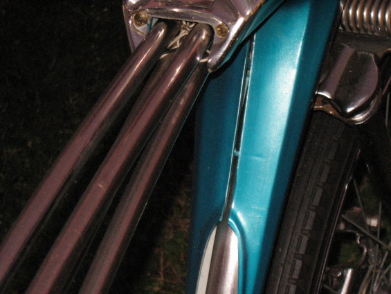 Close-up of chrome handlebars and teal fender on a motorcycle