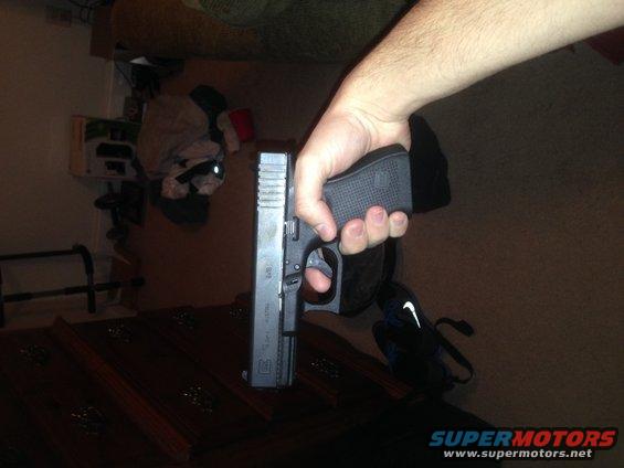 hand holding a black pistol with a textured grip