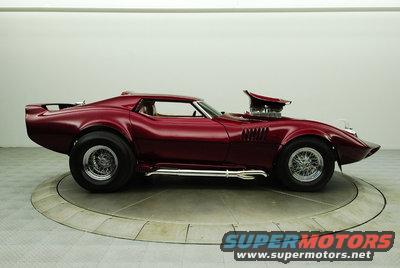 Red 1976 Chevrolet Corvette with a prominent hood scoop and side pipes, shown on a turntable