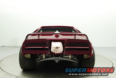 Rear view of a dark red custom car with a skull-like object in the license plate area and wide rear tires