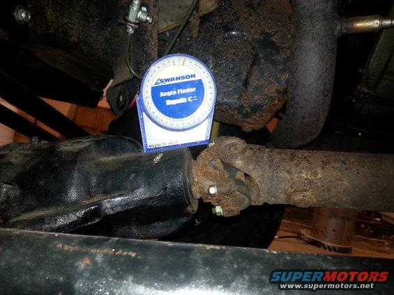 Swanson angle finder tool attached to a rusty driveshaft near a differential