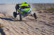 1996 Ford Bronco - An off-road buggy jumps over a dirt mound during a race.