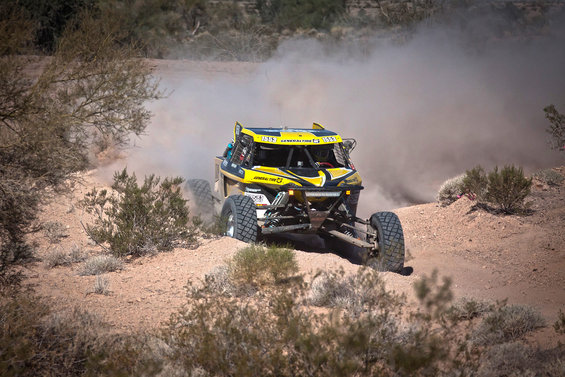 Yellow and black off-road buggy kicking up dust on a dirt track