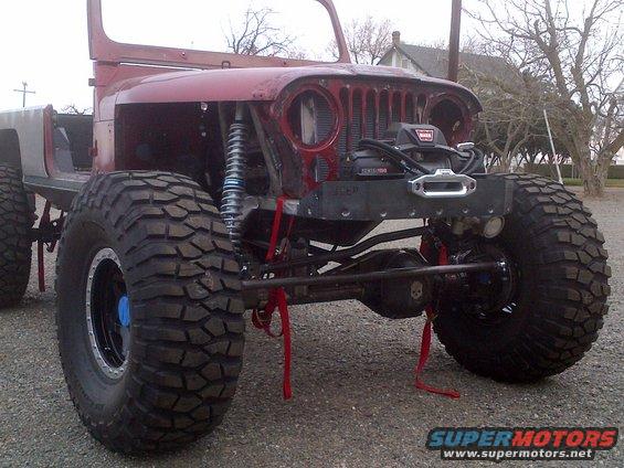 Red Jeep CJ-series body with large off-road tires and a winch