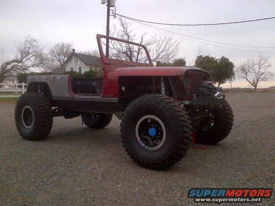 Red Jeep CJ-series with large tires and custom bodywork, front view