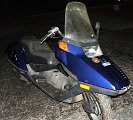 Blue scooter with a tall windshield and orange turn signal