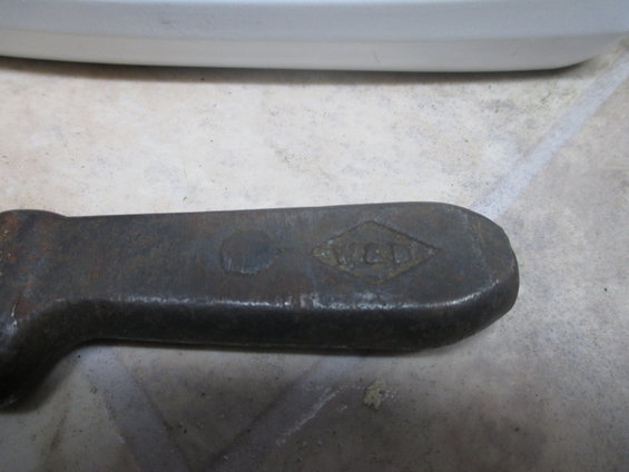Close-up of a rusty metal tool with a diamond-shaped stamp that reads 'W.C.D.'