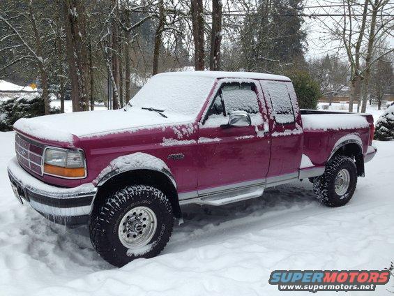 Purple Ford F-150 pickup truck covered in snow, parked outside