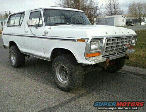 White 1978 Ford Bronco with aftermarket wheels and tires, parked on asphalt