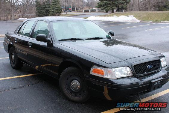 Black 2005 Ford Crown Victoria parked in a lot, front passenger side visible, wet surface