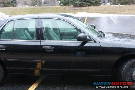 Side view of a black 2005 Ford Crown Victoria with tinted windows and a police spotlight