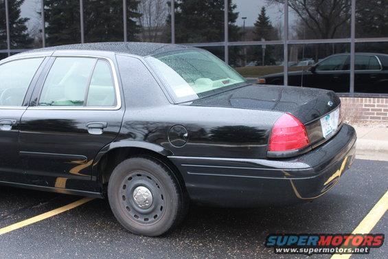Black sedan parked in a lot, reflection of another car in the window