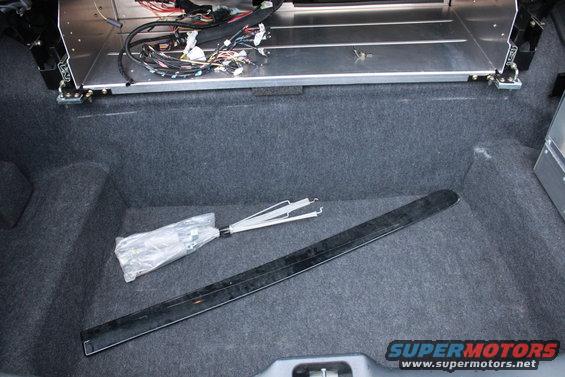 Car trunk with wiring and some parts inside. Supermotors.net logo visible