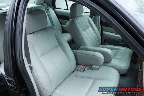 Car interior with light gray leather seats and wood trim. Shows front and rear seats