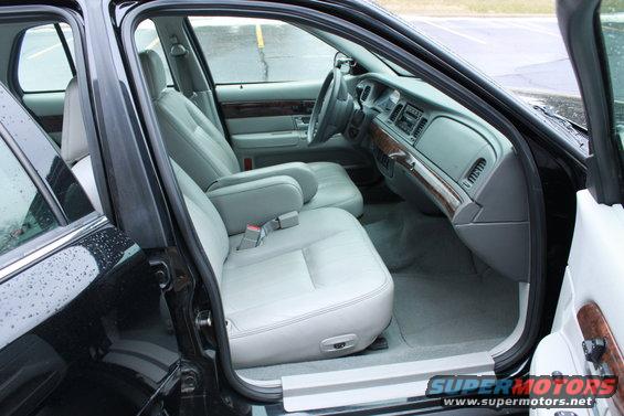 Black car interior with light gray seats, wood trim, and dashboard visible