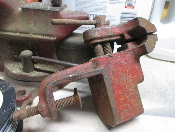 Red metal vise with screw mechanism and clamp
