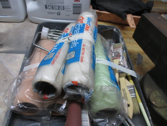 Paint rollers and brushes in a tray. Some rollers are still in plastic packaging