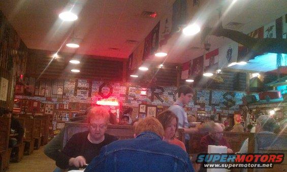 People eating at tables inside a restaurant decorated with license plates and flags