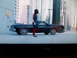 1994 Jeep Cherokee - A person in a superhero costume walks past a black coupe in an urban setting.