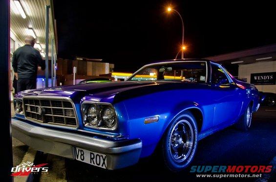 Blue coupe utility with custom plate 'V8 ROX' parked at night