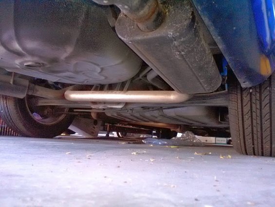 Underside view of a car, showing the exhaust system, fuel tank, and rear tire