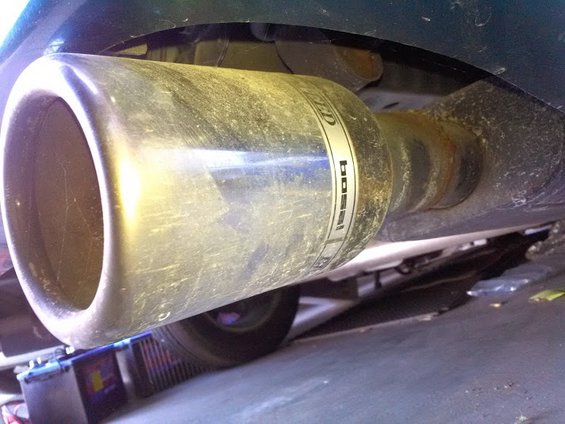 Exhaust pipe with 'Boss' branding, viewed from below, showing rust and dirt