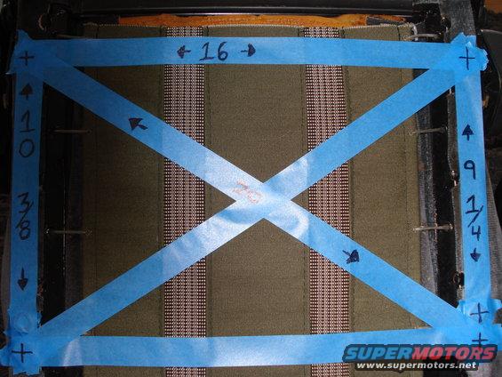 Car seat fabric with blue tape forming an X and rectangle, marked with measurements