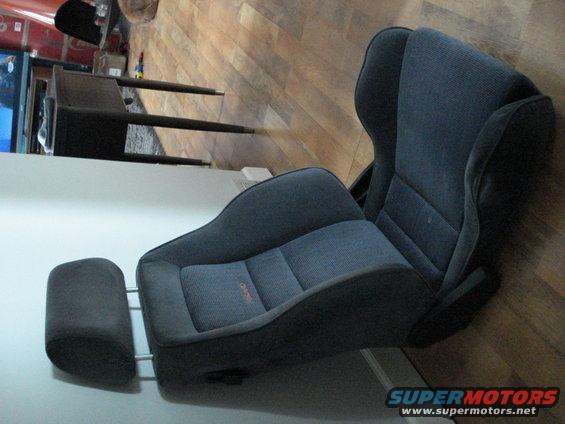 Dark gray car seat with adjustable headrest, orange stitching visible on the seat cushion