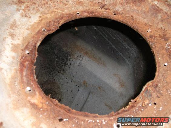 Close-up of a rusted metal opening with small drain holes around the perimeter