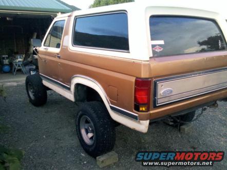 Ford Bronco, tan and white, lifted with large tires, parked in driveway